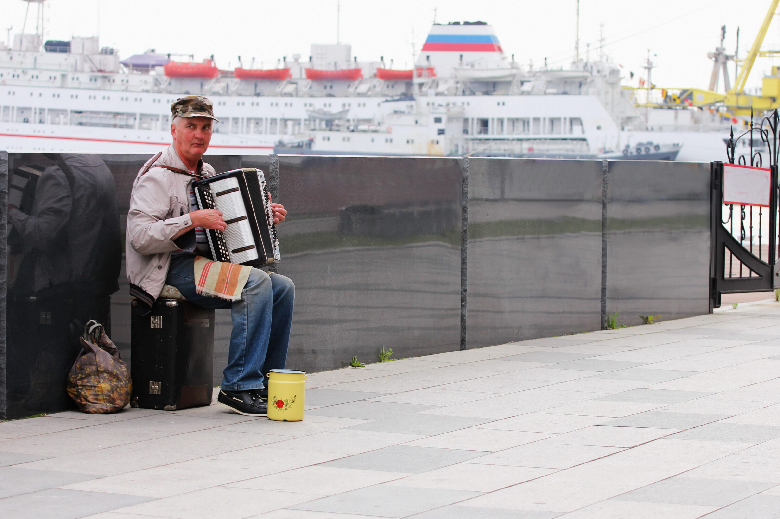 Vladivostok, Russia - 3 Jun 2019 : An elderly man plays the accordion on the waterfront to earn some money for a living. No one around.